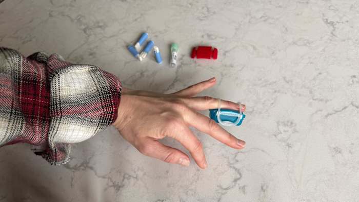 A woman using the phlebitic assistant included in the LetsGetChecked Cholesterol test kit to prepare for the blood sample collection.
